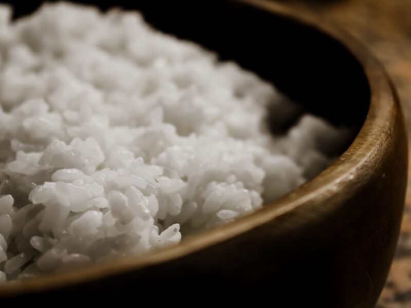 A detailed close-up view of freshly steamed white rice served in a wooden bowl.
