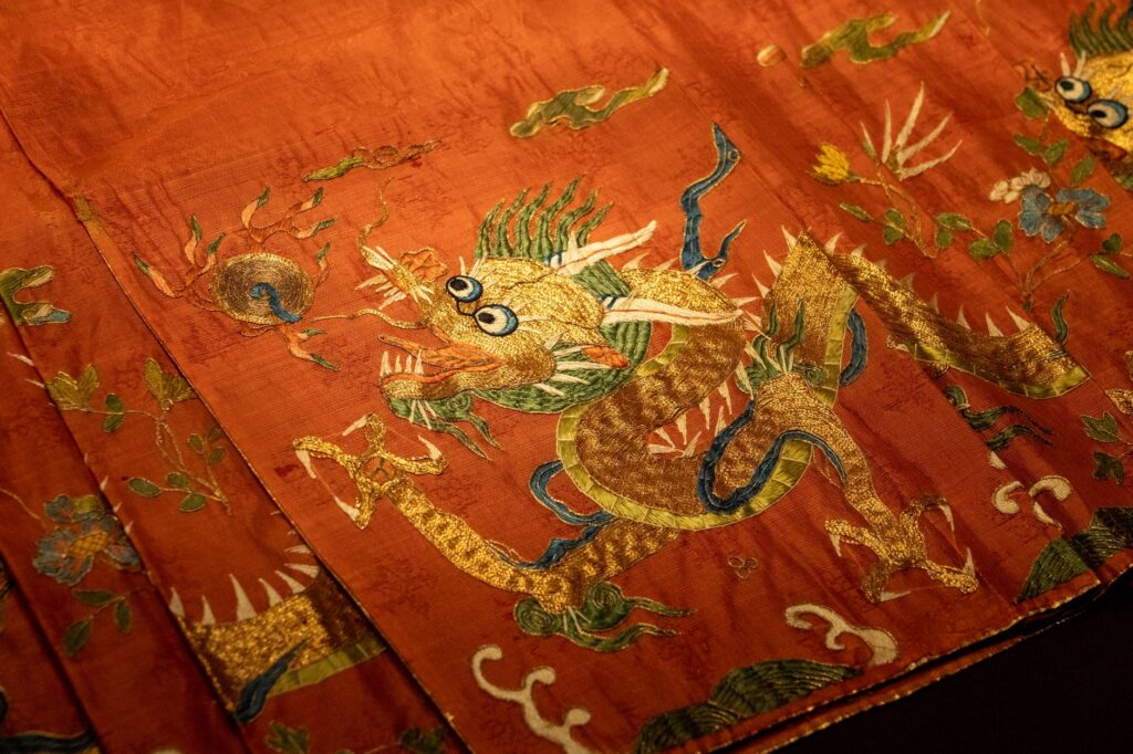 Close-up of an ornate dragon embroidery on red silk fabric showcasing traditional art.