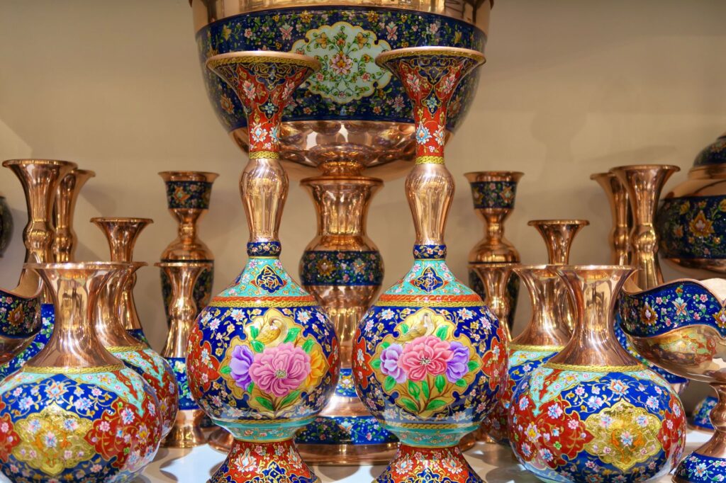 Vibrant Persian copper enamel vases with intricate floral designs, displayed in a shop in Tehran, Iran.